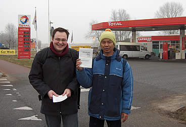 Bert Peterse (links) en Kilo Mike Aye delen folders uit bij Total